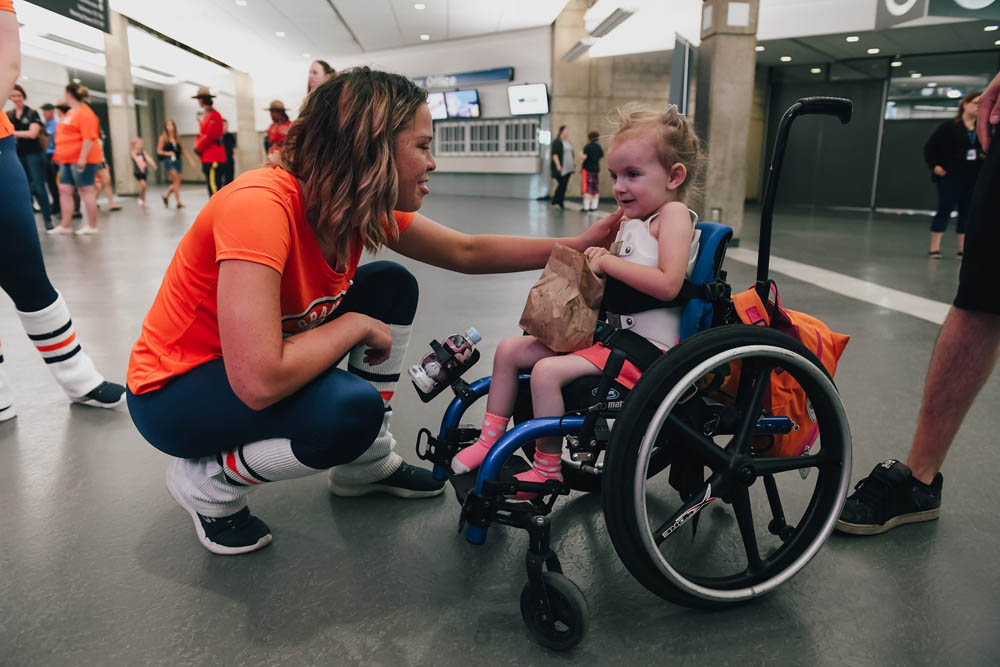 young child in a wheel chair with volunteer saying hello on monday morning magic at k-days