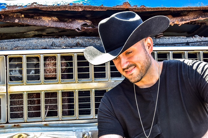 Jason Benoit poses in a cowboy hat looking down.