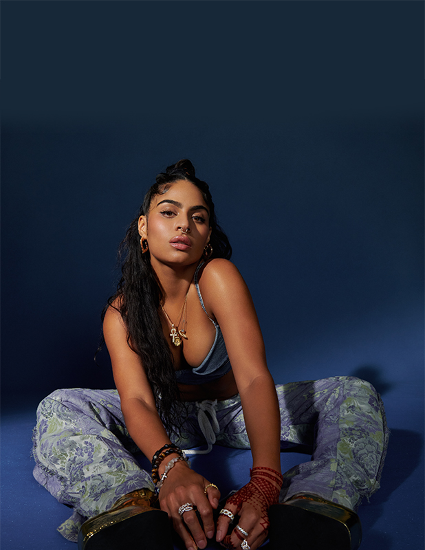 Jessie Reyez sits on a blue carpet while posing for a photo shoot.