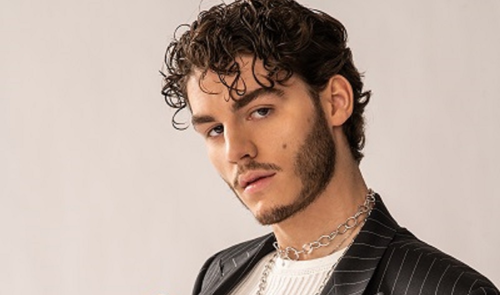 Ryland James poses in a white shirt and black suit jacket.