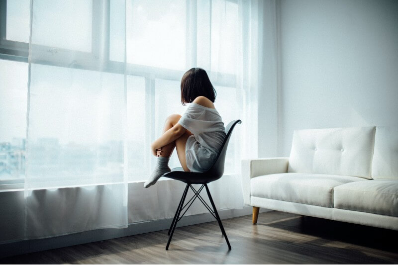 woman sitting on a black chair facing the windows