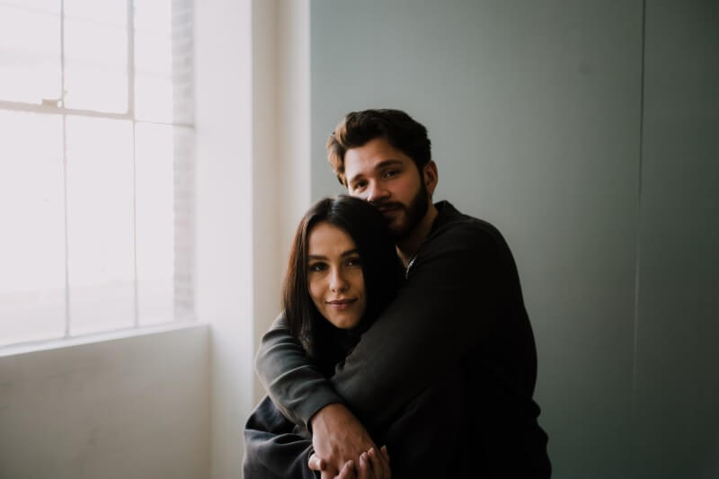 a couple hugging and lightly smiling