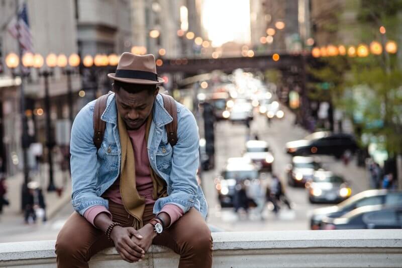 a man looking down while sitting on a ledge