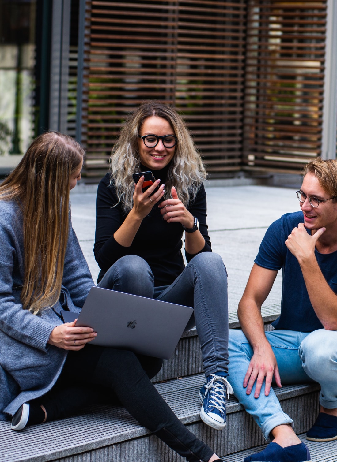 Three Xclaim team members sitting outside on steps