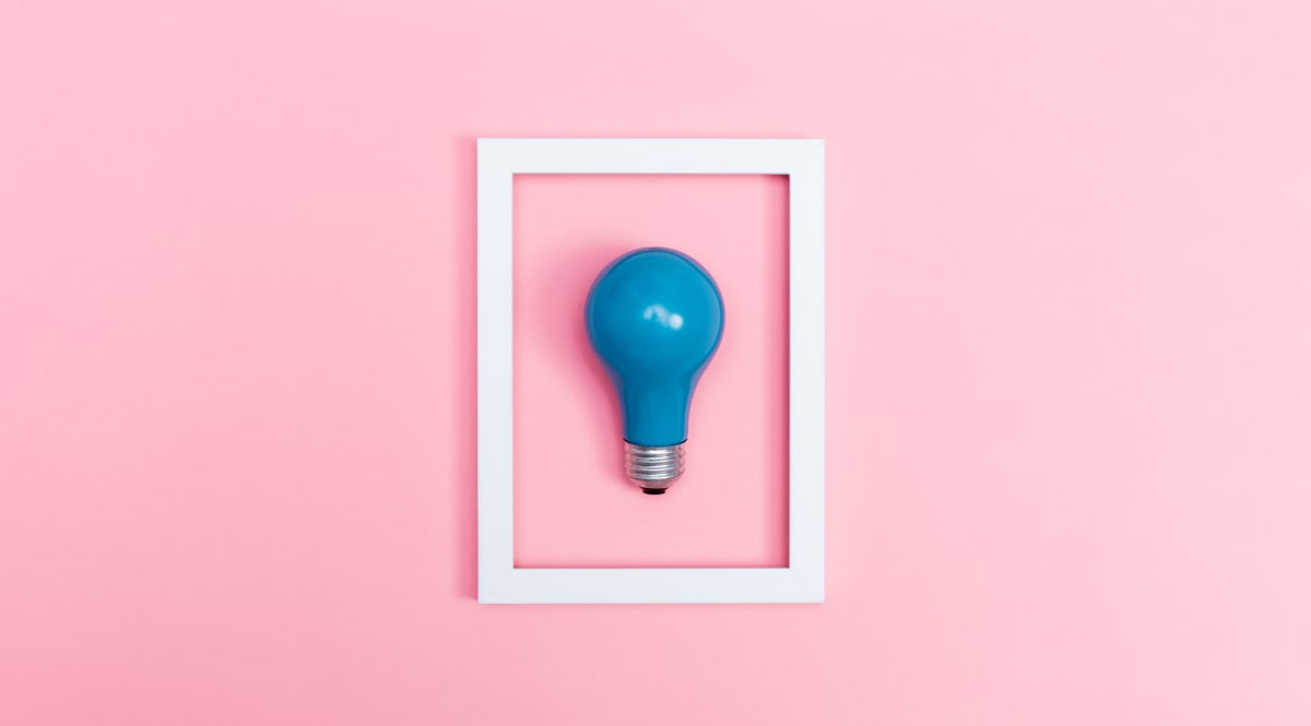 Blue lightbulb in a white frame against a pink background