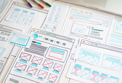 Papers with a rough sketch of a website layout on them