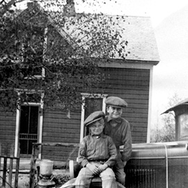 Photo taken in the 1920's of our farmhouse that was built in 1911 with two children sitting on the hood of a really old car.