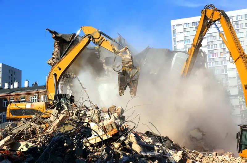 pulveriser being used on a demolition site attached to an yellow excavator