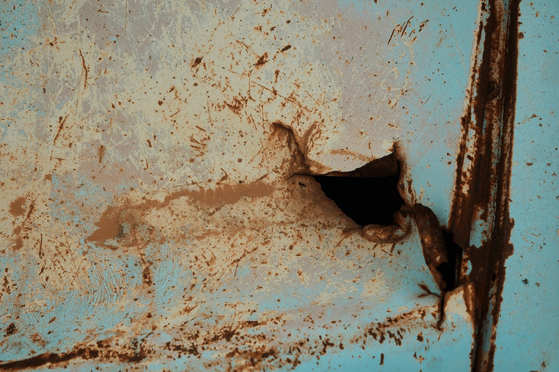 badly rusted pannel on a blue machine