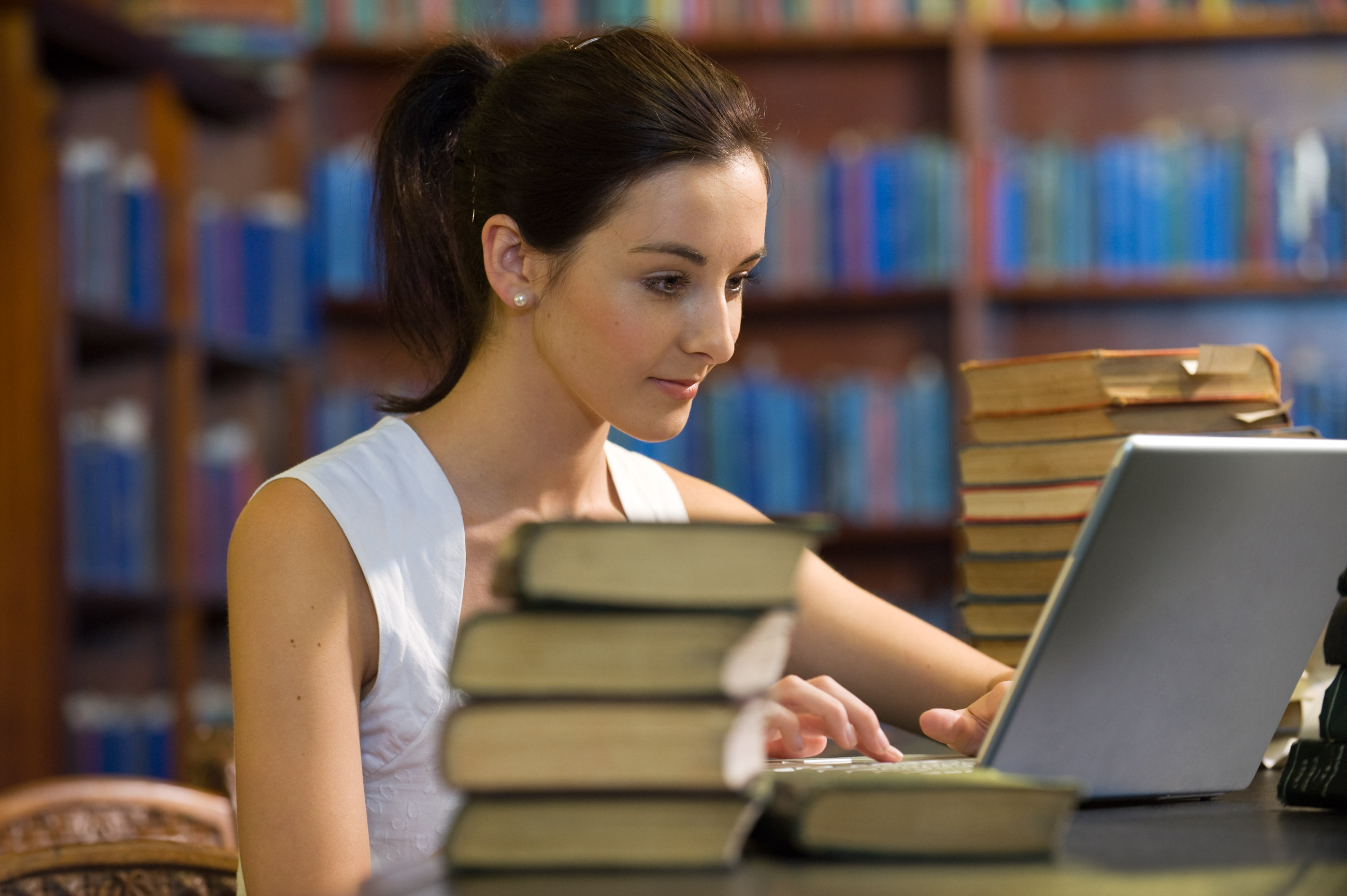 Girl using laptop and books for online learning