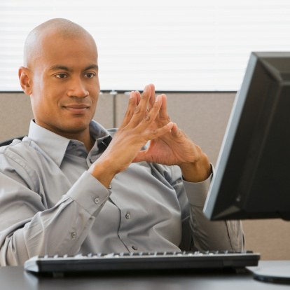 Contented businessman contemplates monitor