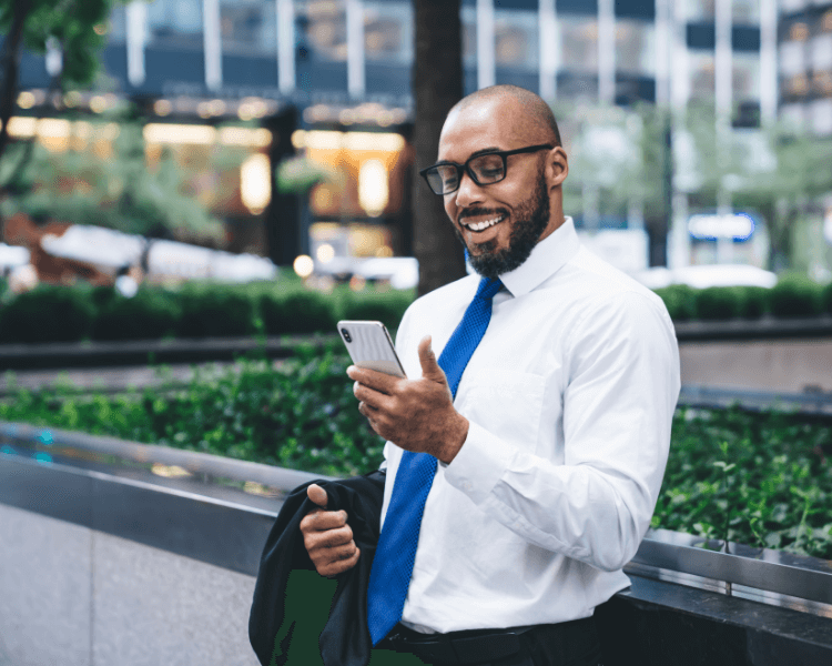 Man wearing a suit smiling at his phone.