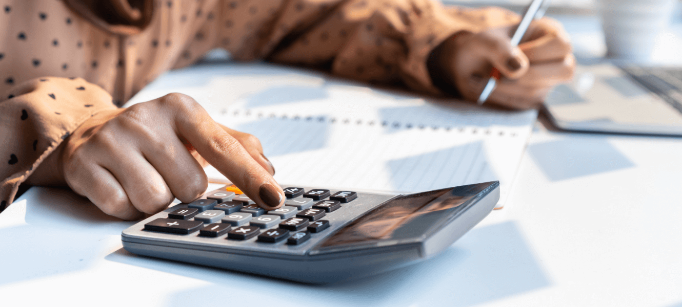 A woman using a calculator and taking notes on paper.