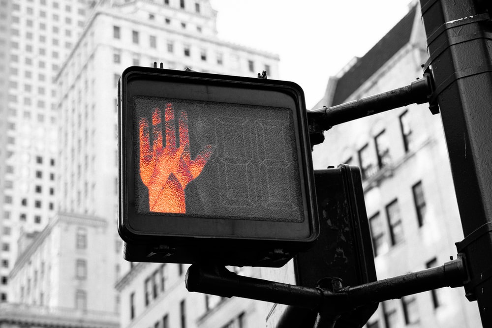 A crosswalk signal with the stop hand lit up.