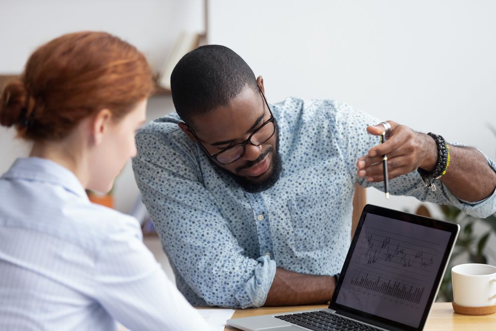 A man going over a graph on a laptop to a woman