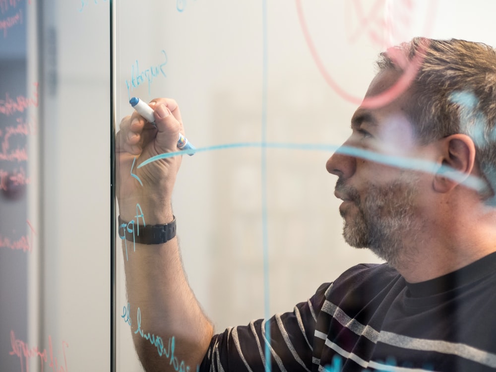 A man whiteboarding on glass.
