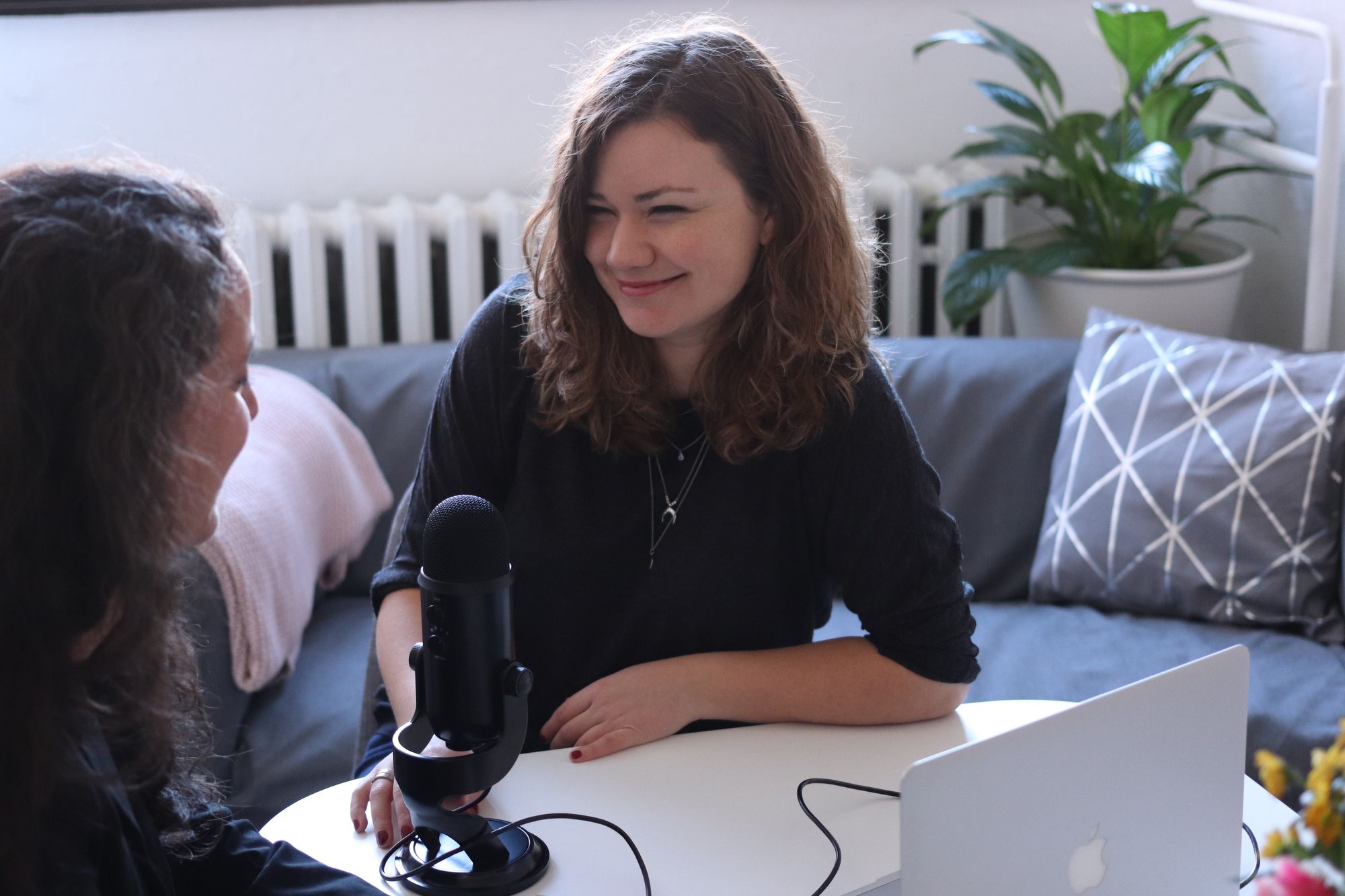 2 women talking with a microphone between them and a laptop near by.