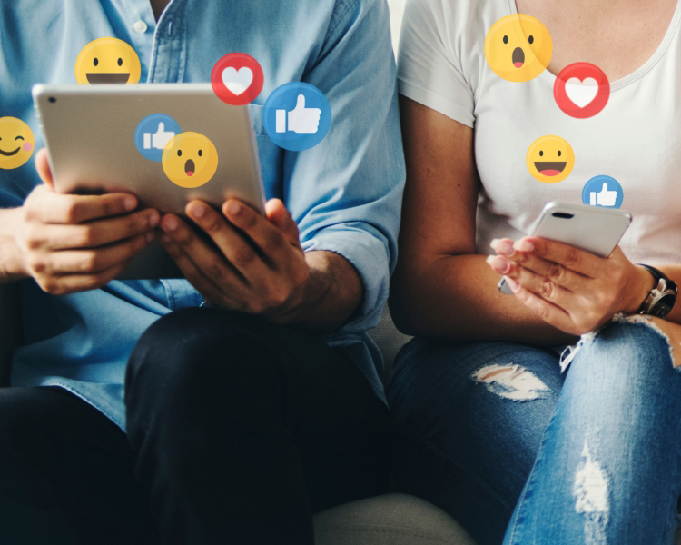 Close up of people sitting together on their devices with social media likes, hearts, and reactions floating around.
