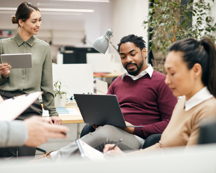 A group of people in a working meeting on notepads and devices.