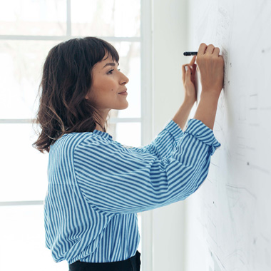 brunette woman writing on whiteboard