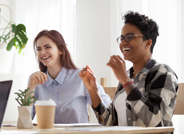 Two women on meeting table laughing