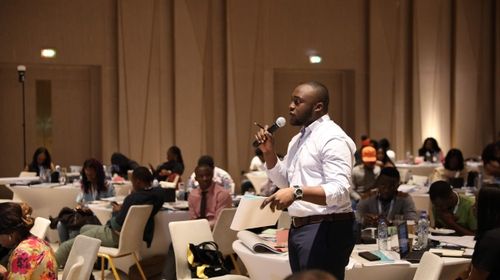 Image of Charles Njoku holding a mic and speaking