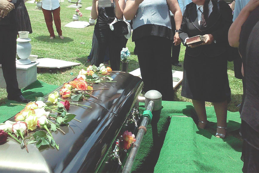 A casket at a funeral being prepared to be lowered into the ground