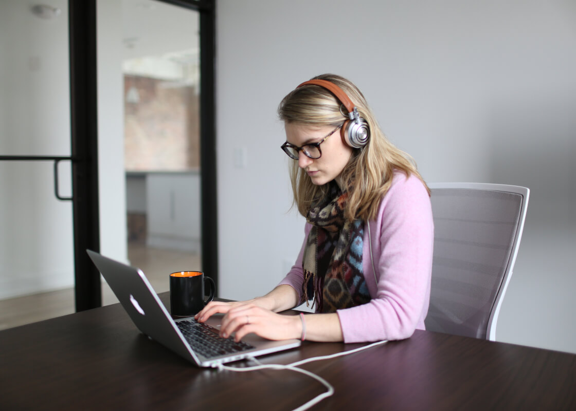 girl in glasses with headphones using notebook