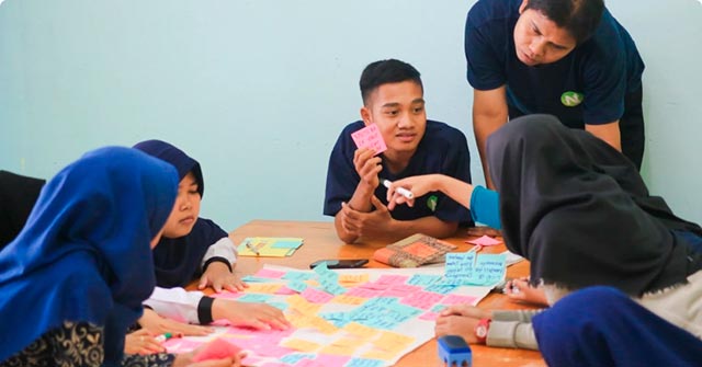 A few people around a table pasting postits