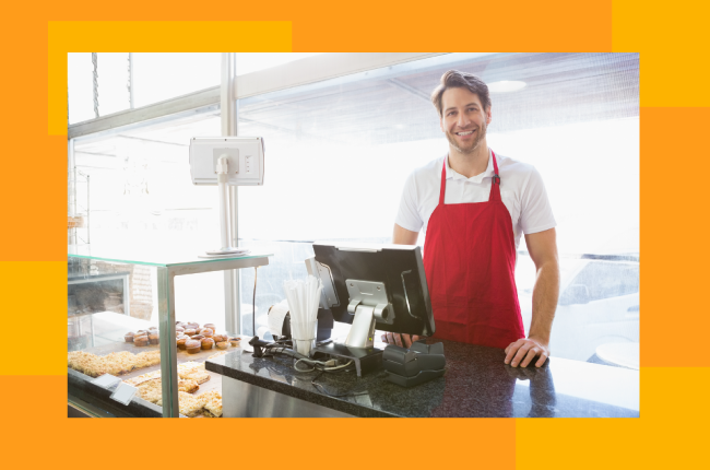 retail worker in red apron standing at counter smiling at camera