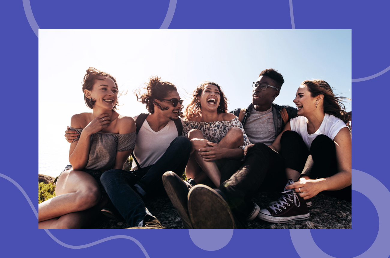 Group of young friends sitting in the sun smiling and laughing together