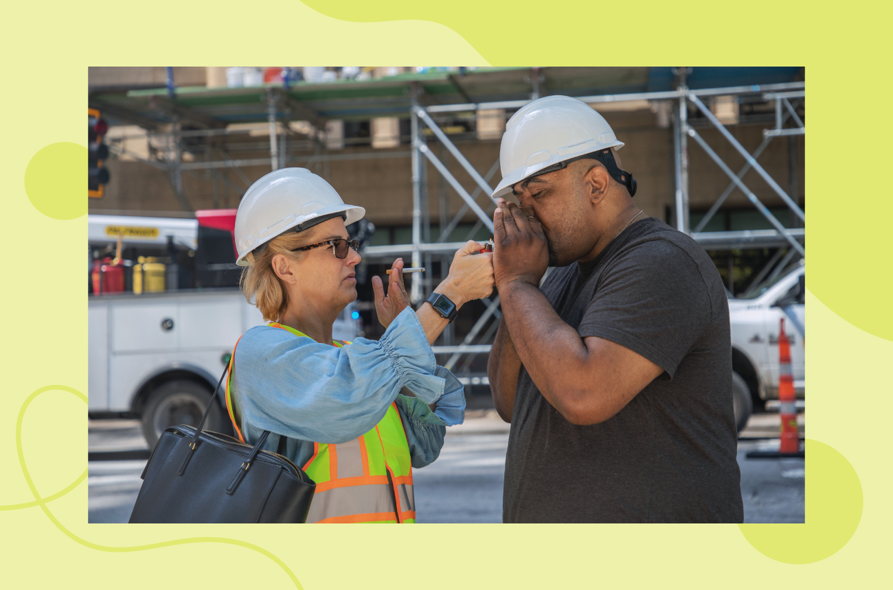 Male and female manufacturing workers smoking cigarettes together