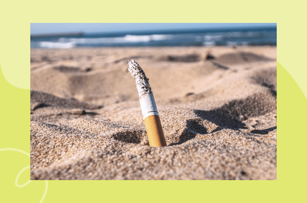 Single littered cigarette sticking out of the sand on a beach