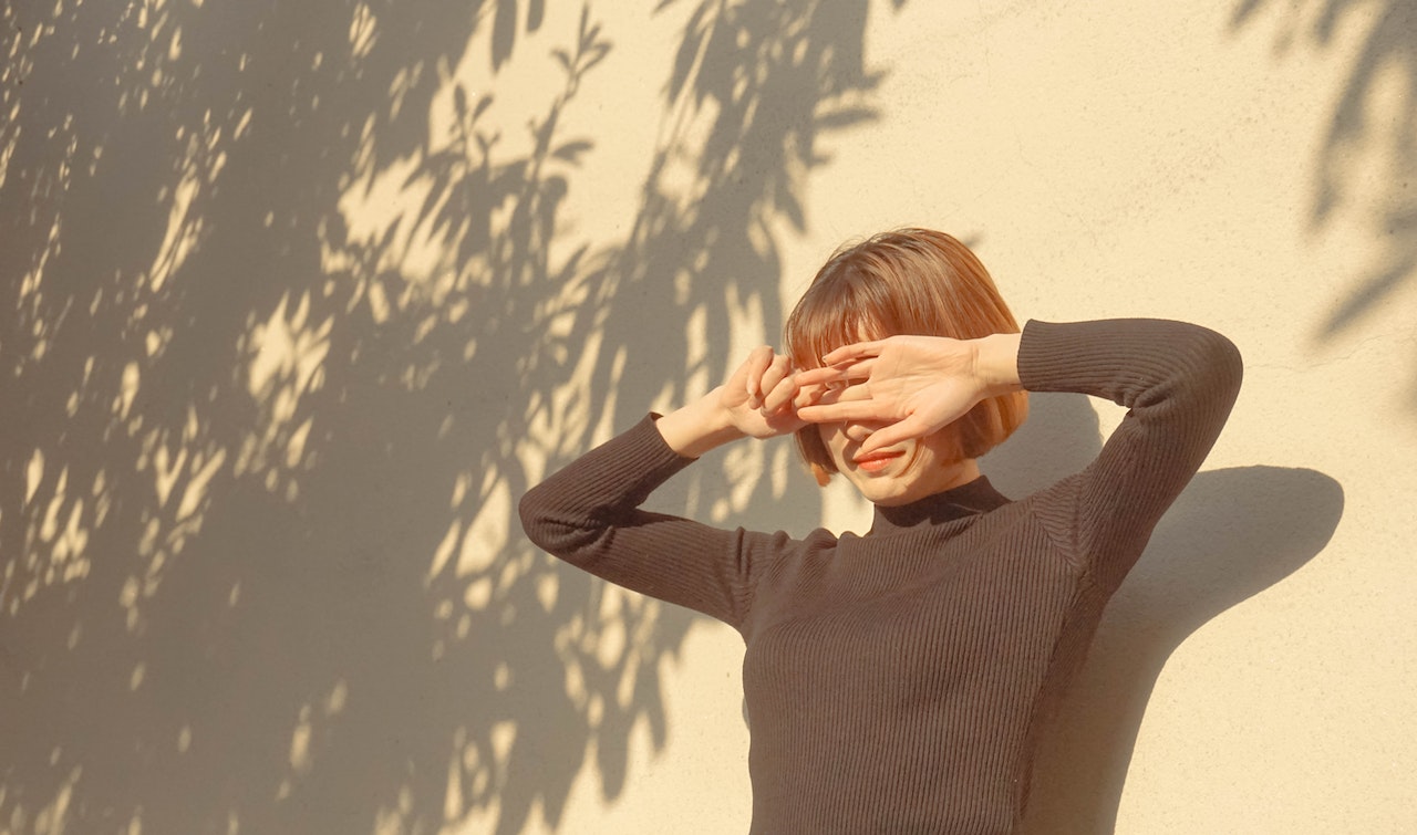 woman covering her face while being sun kissed 