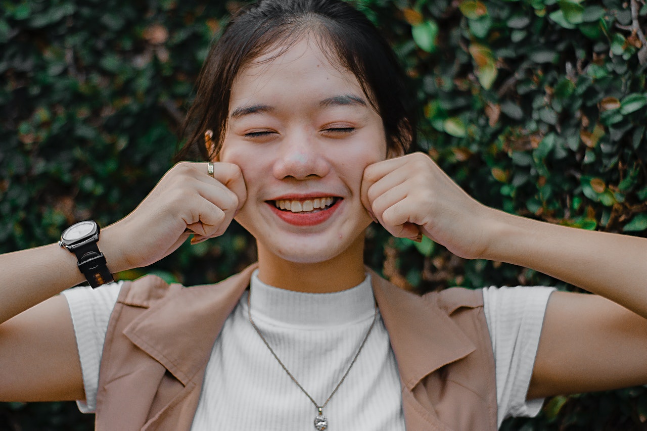 smiley woman pinching her own cheeks