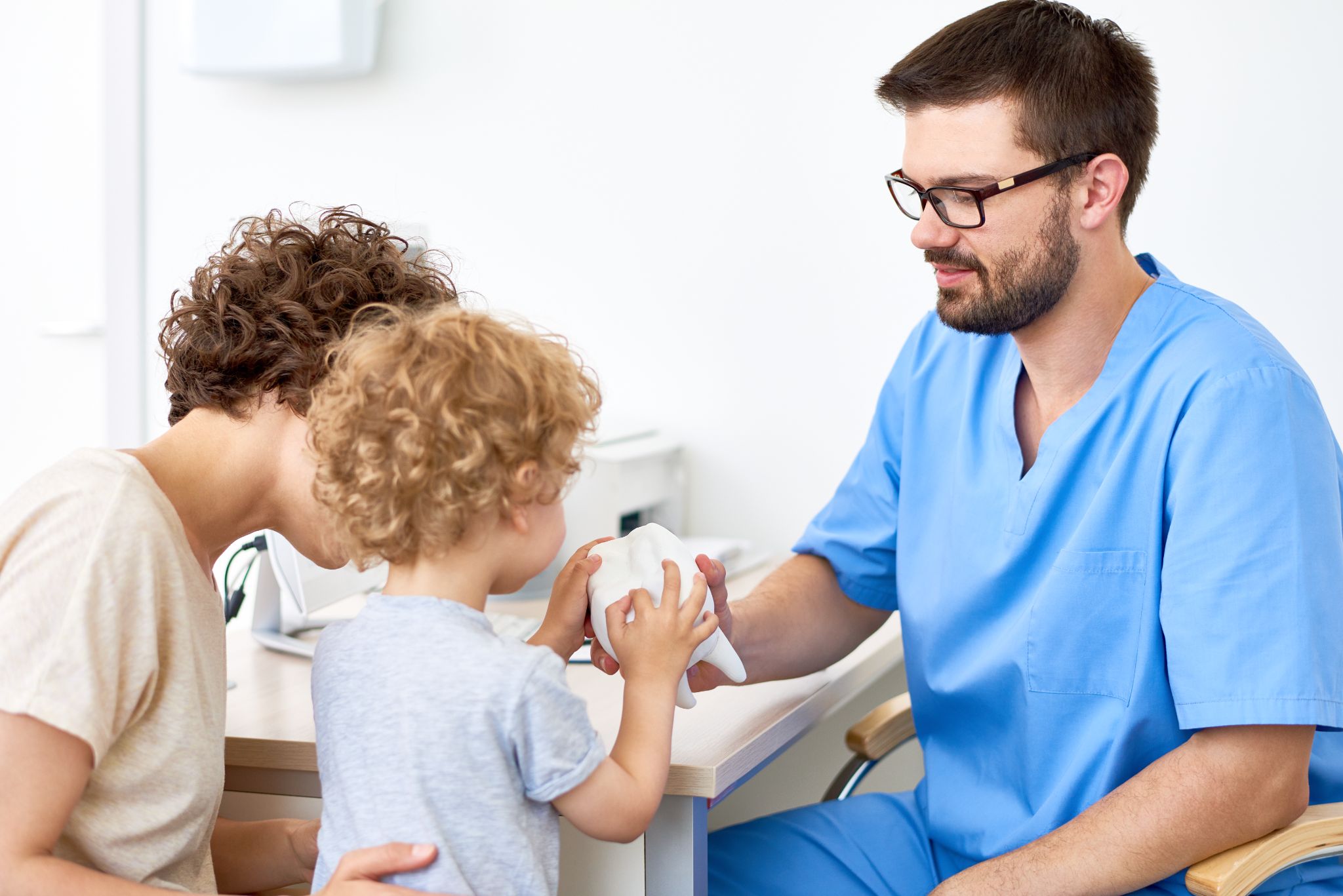 doctor lets young patient examine a model tooth