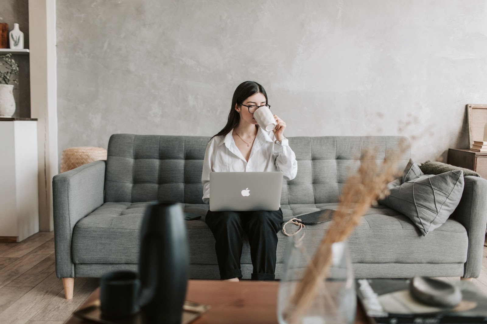 A Christian student sitting on a couch studying while drinking a coffee