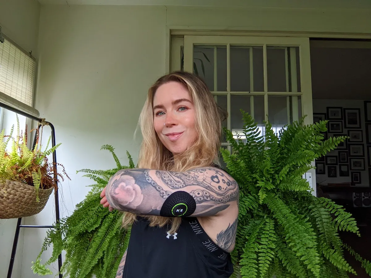 A Nutrisense member named Meredith Standridge folding her left arm with a Nutrisense cgm sensor on her upper left hand.