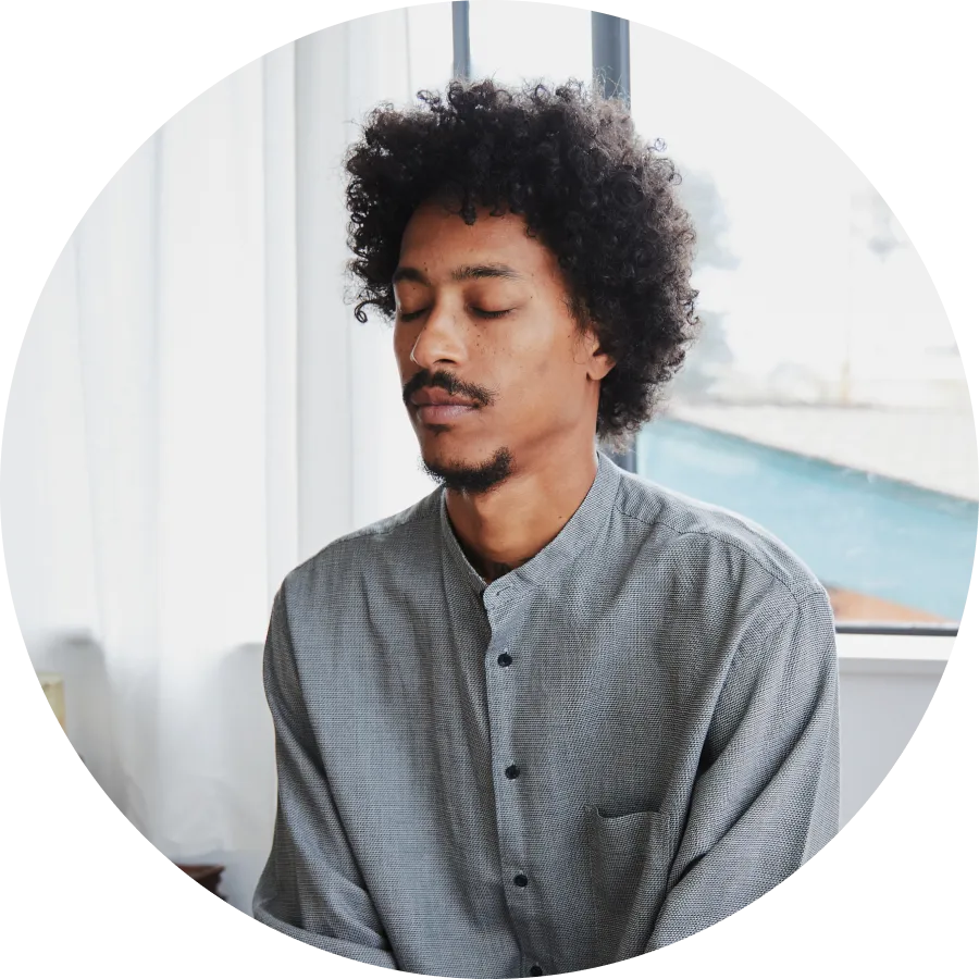 A man sitting with closed eyes practicing stress management skills.