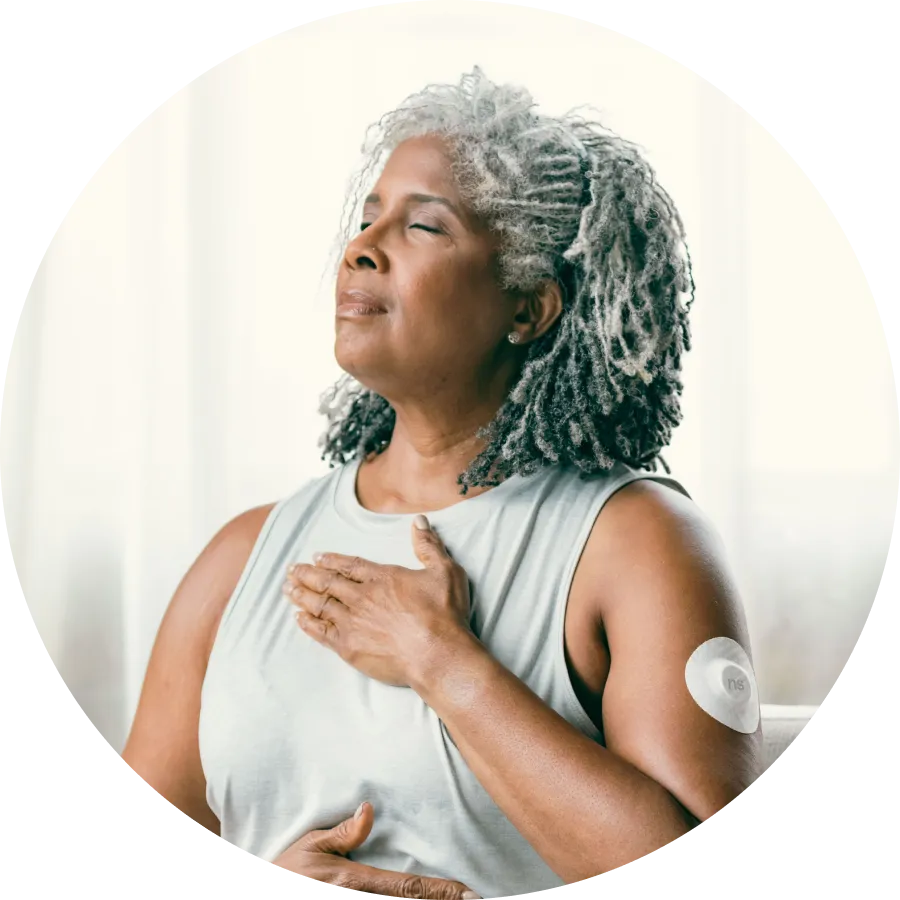 A woman placed her left hand on her chest with Nutrisense CGM device on her upper left hand available at nutrisense.io