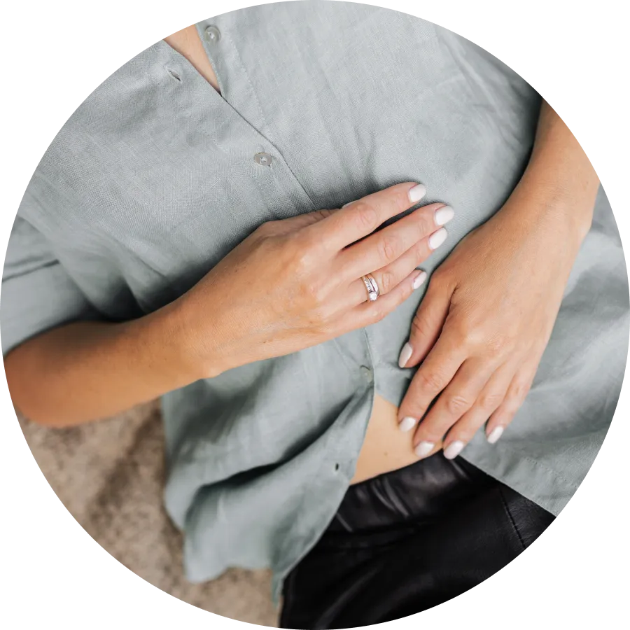 A woman placed her hands on her stomach while laying on bed.