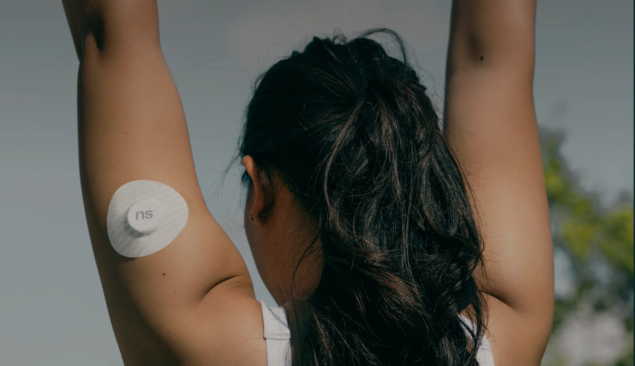 Upper back view of a Nutrisense member wearing a cgm sensor on her upper left hand.