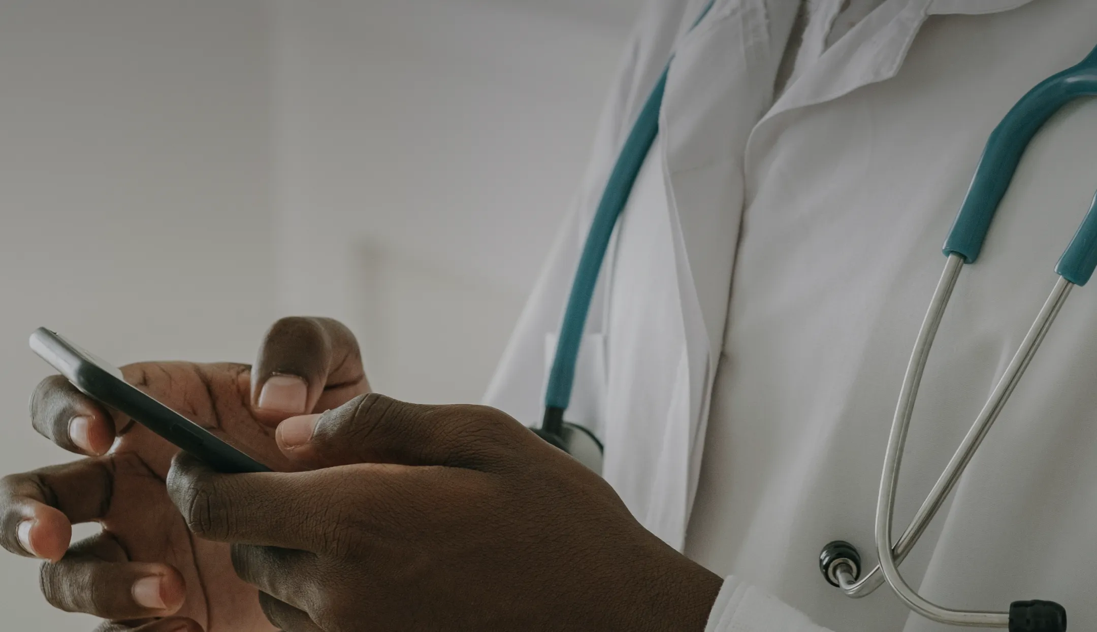 Hands of a male doctor holding a phone with green silicone cover.