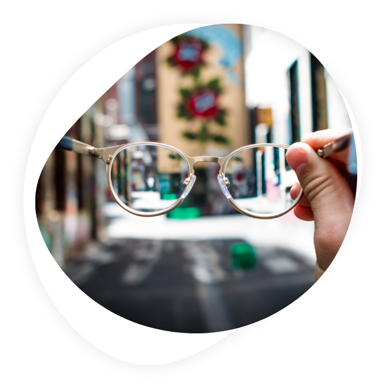Glasses held up to a bring focus on a city street