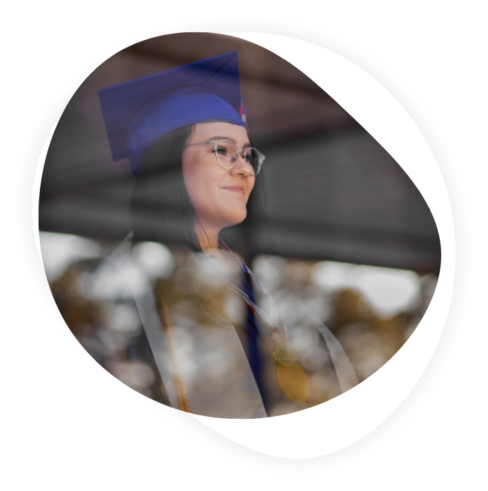 Graduate in regalia looks out a window
