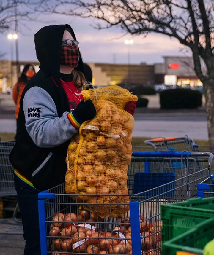 Food bank worker with sack of potatoes