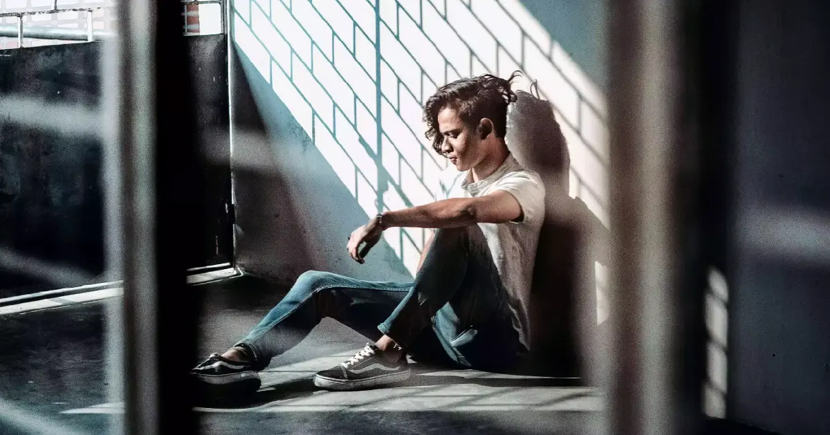 A teen sits alone on the floor at school dealing with PTSD