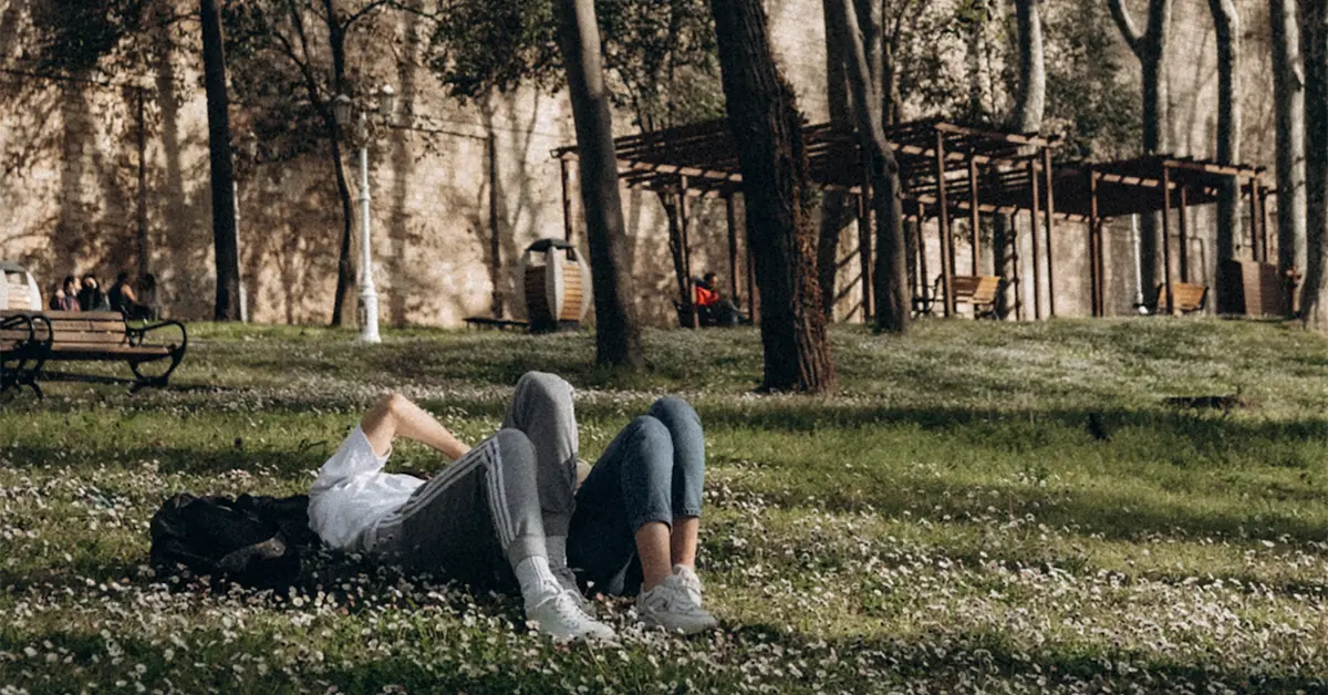 A teen couple lays in the grass during springtime