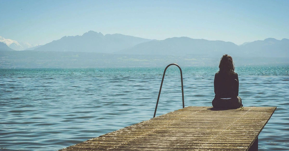 person on edge of lake contemplating life