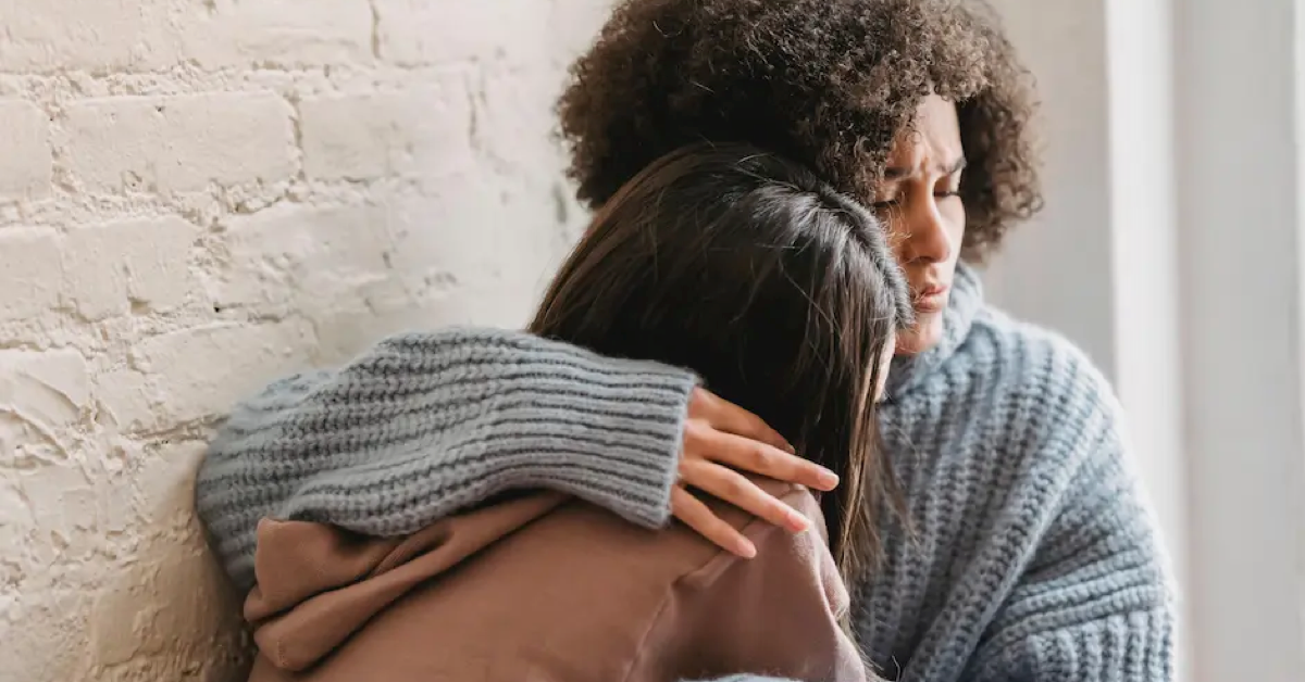 Parent hugs teen in pain